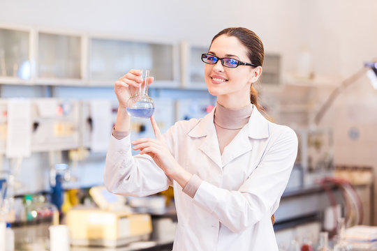 Woman scientist in laboratory with beaker posing