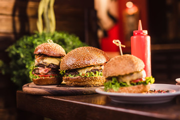 Three juicy and tasty burger with ketchup bottle on the table in a restaurant