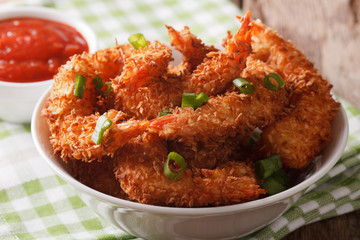 Fried shrimp in coconut breaded close up in a bowl and the sauce. horizontal