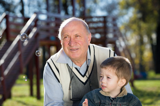 grandfather and grandson looking for soap bubbles in a park