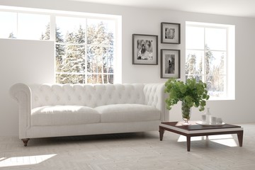 White room with sofa and winter landscape in window. Scandinavian interior design