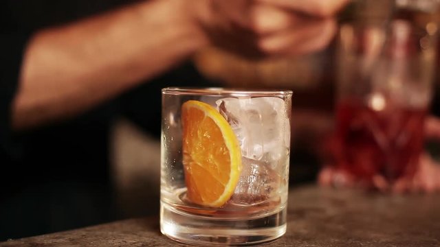 Bartender pouring negroni into glass