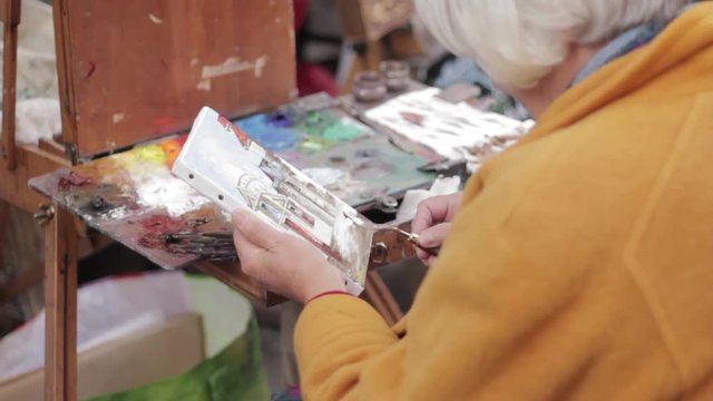 Street artist working on oil painting