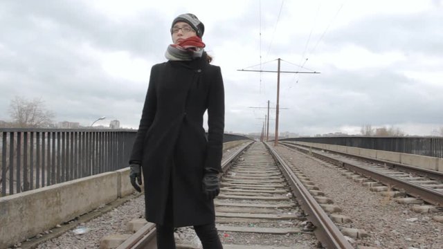 Girl teenager stands on the tram bridge, turns and walks away