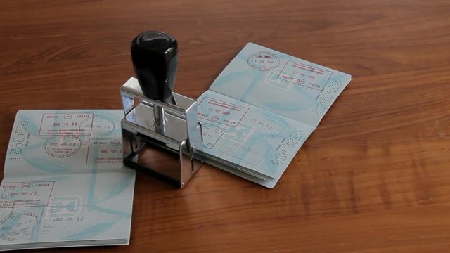 Passports and Stamp on Brown Wooden Desk.