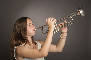 woman playing trumpet on a gray background