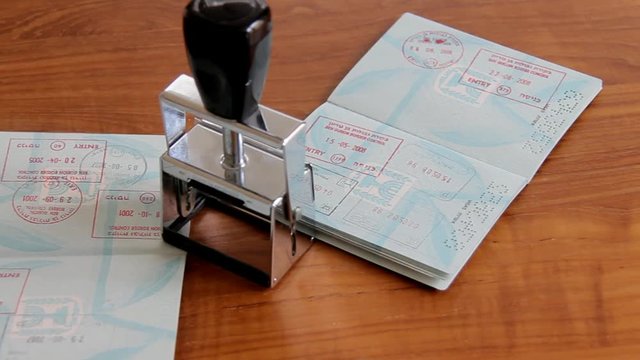 Passports and Stamp on Brown Wooden Desk.