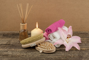Beautiful composition with white candle, aromatic oil and massage brushes on wooden background