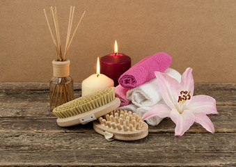 Beautiful composition with white candle, aromatic oil and massage brushes on wooden background, body and ckin care concept