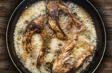 Fish in a frying pan. horizontal view from above. On the wood