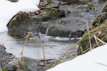 Small waterfalls flowing river with snow.