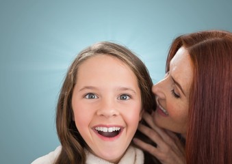 Mother speaking at her daughter ear against a blue background  