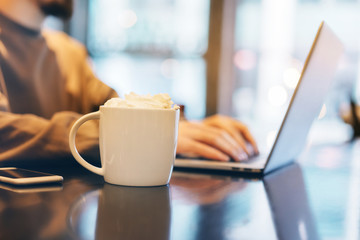 Mock-up of cup of coffee for your logo or creativity design, Man working in coffee shop, Workplace in the early morning, Shallow DOF