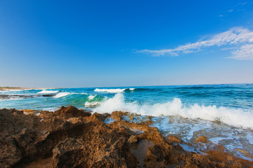 Fototapeta na wymiar Huge wave breaking over rocks with dramatic foam and brilliant sea coast line morning, Cyprus