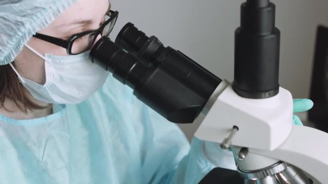 Close up view of scientist eye in glasses looking at microscope.