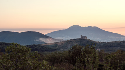 Fototapeta na wymiar Il panorama con la vista sul Vesuvio al tramonto e collina con antico castello longobardo in regione Campania, Italia
