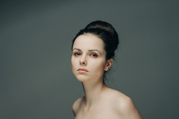 dark-haired woman on a gray background looks at the camera