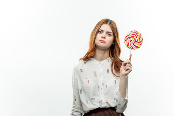 round lollipop in the hands of a happy woman in a shirt and a skirt