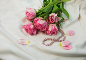 Bouquet of pink tulips and a pink pearl necklace.