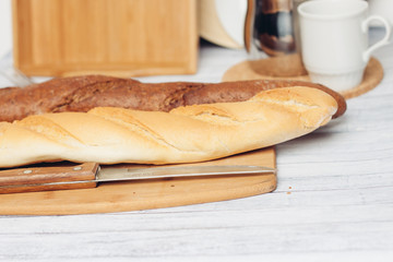 two baguettes on the board and a knife with a wooden handle