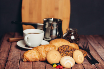 biscuits, croissants and colorful candy, white cup