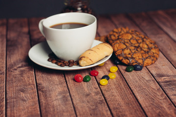 cup with a drink and colorful candy with a cookie on the table