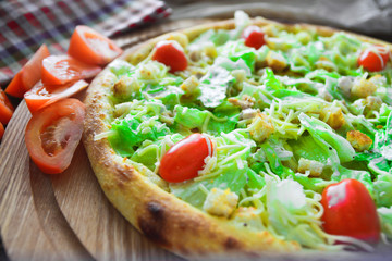 Pizza with tomatoes and greens on a cutting board
