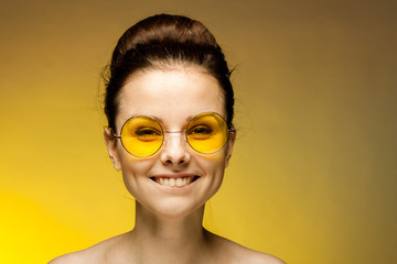 happy woman in yellow glasses smiles at the camera