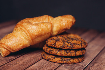 oatmeal cookies and croissant on a wooden background