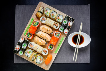 Sushi rolls and sauce with chopsticks on black background. Japanese food. Top view. Flay lay