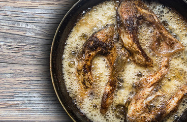 Fish in a frying pan. horizontal view from above. On the wood