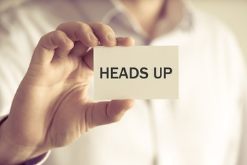 Businessman holding HEADS UP message card