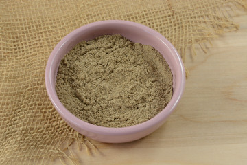 Ground decorticated cardamon spice in pink bowl