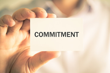 Businessman holding COMMITMENT message card