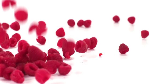 Raspberries fall onto a white cyc in slow motion