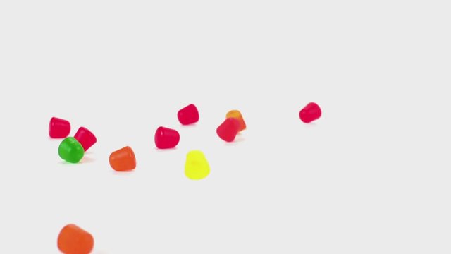 Gummy candy tumble and fall in slow motion onto a white cyc