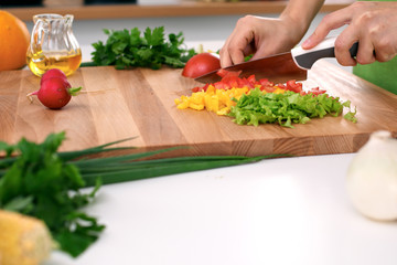 Close up of  woman's hands cooking in the kitchen. Housewife slicing ​​fresh salad. Vegetarian and healthily cooking concept