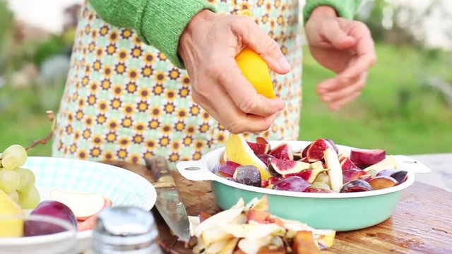 Woman squeezing citrus over cut-up fruits