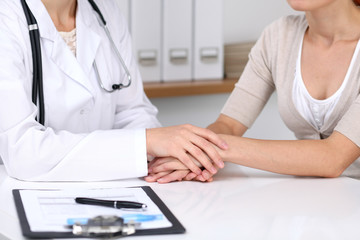 Close up of a doctor reassuring her female patient while  sitting at the desk. Medicine, help and health care concept