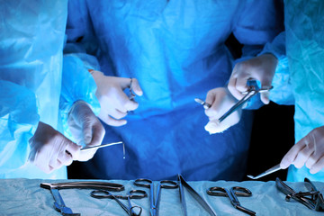 Medical team performing operation. Group of surgeon at work in operating theatre toned in blue.