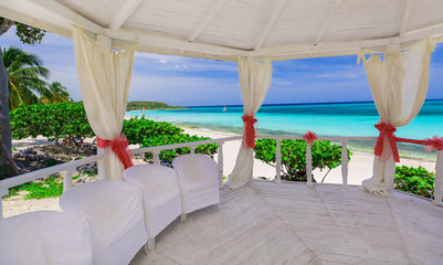 Beautiful amazing gorgeous view from the inside of decorated wedding gazebo against tranquil ocean beach and blue sky background 