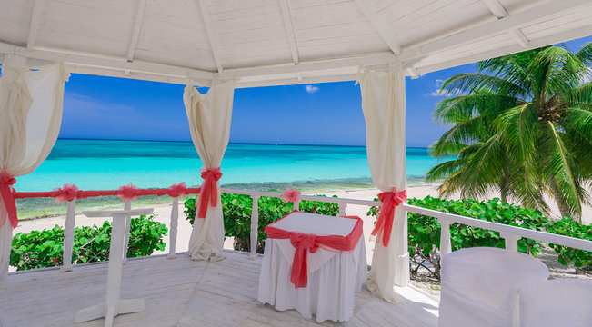 Beautiful amazing, stunning inviting view from the inside of decorated wedding gazebo on tropical beach tranquil ocean and blue sky background 