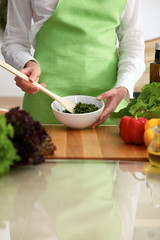 Closeup of human hands cooking vegetables salad in kitchen on the glassr table with reflection. Healthy meal and vegetarian concept