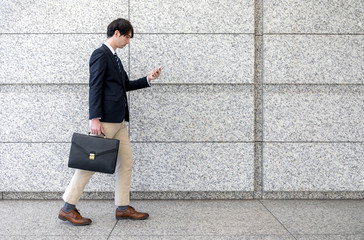 young man texting with smart phone while walking