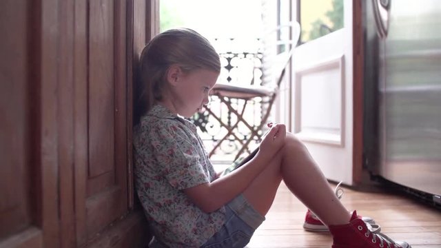 Little girl sitting on floor, engrossed in digital tablet