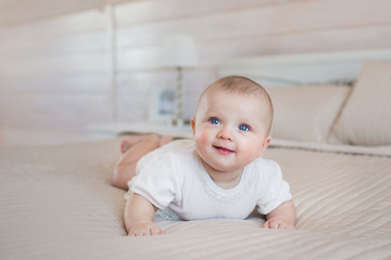 Pretty newborn lies and smiles on a bed at home