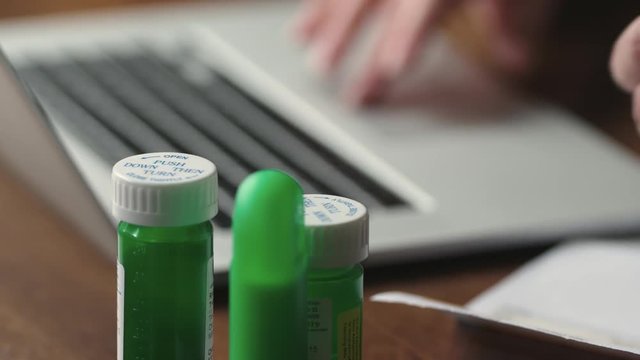 Tracking shot close up of a hand picking up a prescription drug