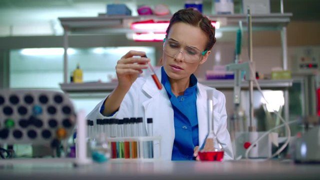 Female scientist working at the laboratory. Scientist cure. Woman scientist check test tube with reagents. Lab scientist observing liquid in laboratory. Worker doing science laboratory research
