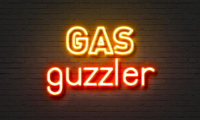 Gas guzzler neon sign on brick wall background.
