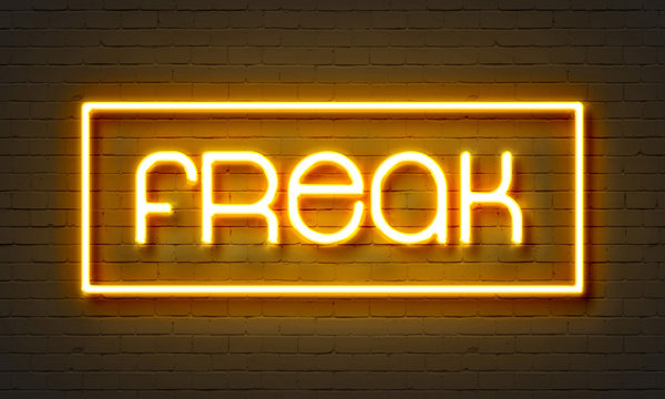 Freak neon sign on brick wall background.